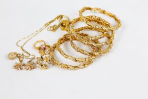 Exklusiva guldsmycken med armband, ringar och halsband på vit bakgrund.