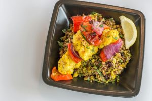 En färgglad vegetarisk bowl med grillade grönsaker och quinoa i en svart skål.