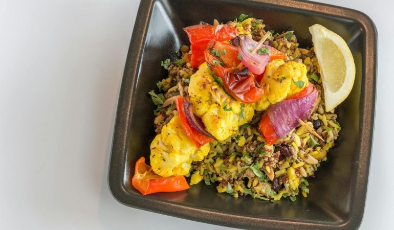 En färgglad vegetarisk bowl med grillade grönsaker och quinoa i en svart skål.